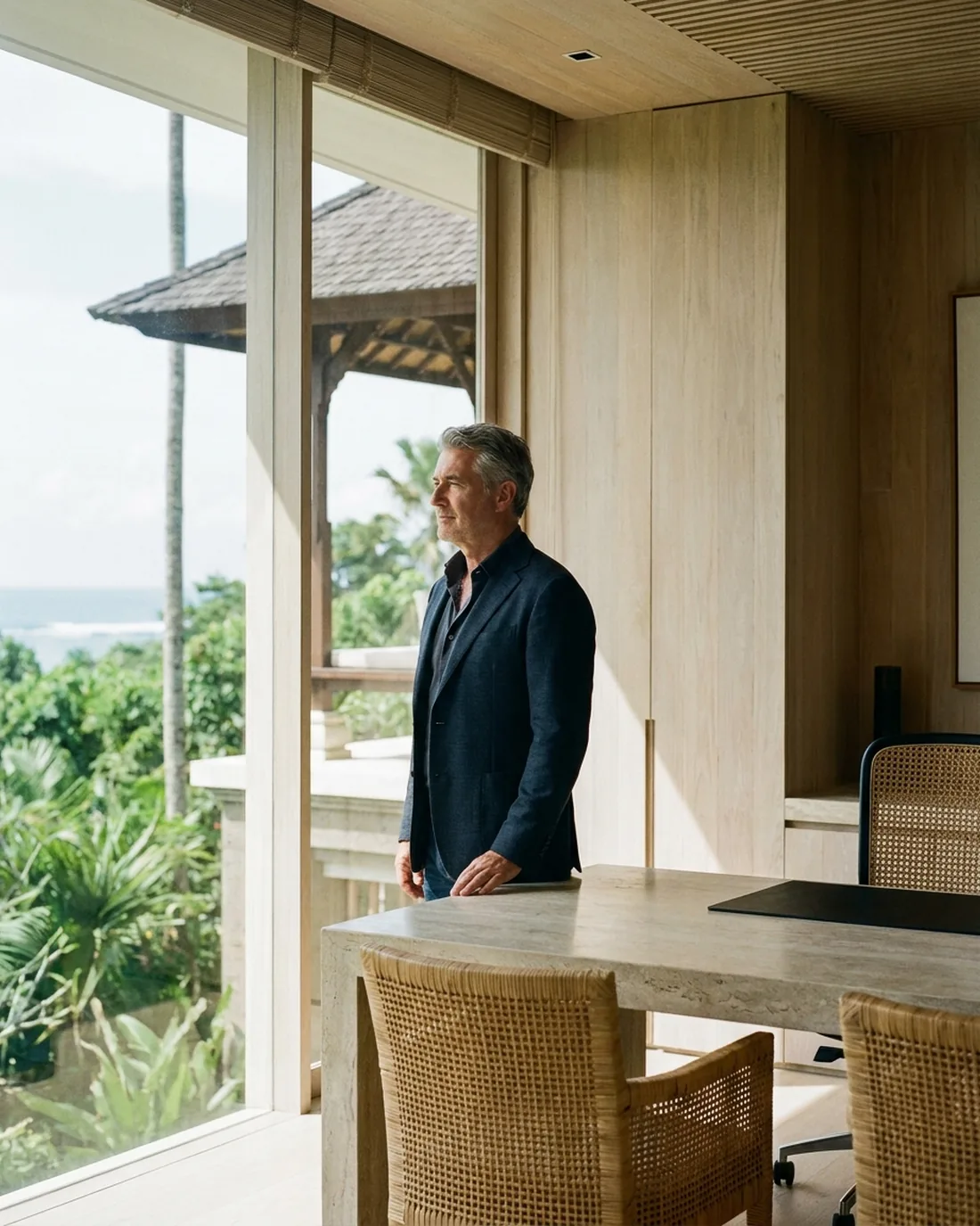 A senior executive standing composed by a window in a quiet office above the city